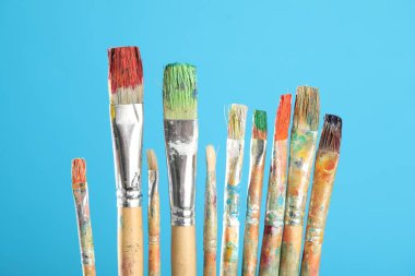 Açık mavi arkaplanda kirli boya fırçaları, yakın plan