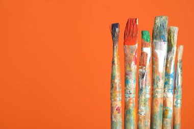 Turuncu arka planda birçok kirli boya fırçası, yakın plan. Metin için boşluk