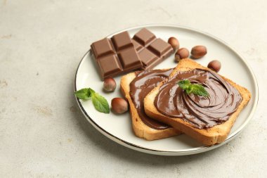 Lezzetli çikolatalı tostlar, parçalar, nane ve fındıklar ışık masasında, yakın plan