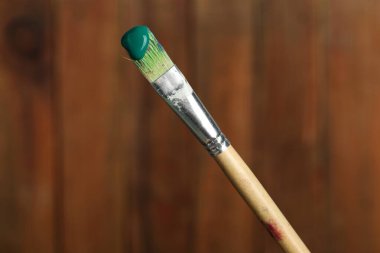 Ahşap arka planda yeşil boyalı fırça, yakın plan.