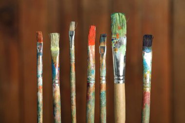 Ahşap arka planda birçok kirli boya fırçası, yakın plan