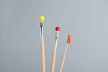 Açık gri arkaplanda renkli üç fırça, yakın plan.