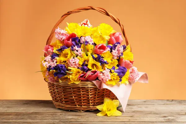 Tahta masanın üzerinde mercan zemin üzerinde güzel çiçekler olan sepet, yakın plan.