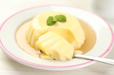 Karamel soslu lezzetli puding ve beyaz masada servis edilen nane şekeri.