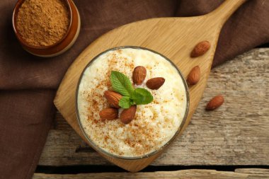 Tarçınlı sütlaç, badem ve nane şekerli ahşap masa, üst manzara.