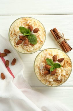 Tarçınlı lezzetli sütlaç, badem ve nane şekerli beyaz ahşap masa, düz uzanmış