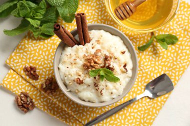 Cevizli, tarçınlı, nane ve ballı leziz sütlaç beyaz masada, düz yerde.