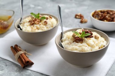 Cevizli, tarçınlı, nane ve ballı lezzetli sütlaç. Gri masada, yakın plan.