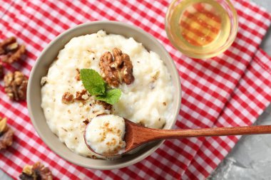 Lezzetli sütlaç kasede, ceviz, nane, bal ve kaşık masada.