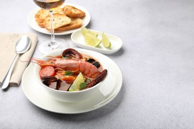 Açık gri masada servis edilen lezzetli deniz ürünleri çorbası, metin için yer.