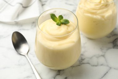 Beyaz mermer masada servis edilen naneli vanilyalı puding, yakın plan.