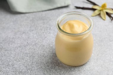 Lezzetli vanilyalı puding, kapsüller ve çiçek gri masada, yakın plan. Metin için boşluk