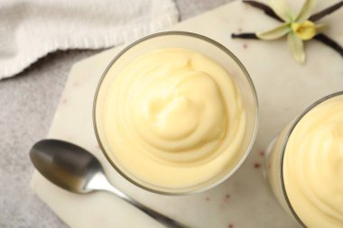 Lezzetli vanilyalı puding, kapsüller ve çiçek gri masada, düz uzanmış