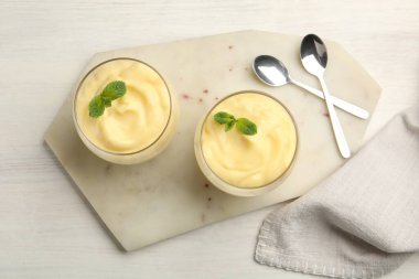 Beyaz ahşap masada servis edilen nane aromalı vanilyalı puding.