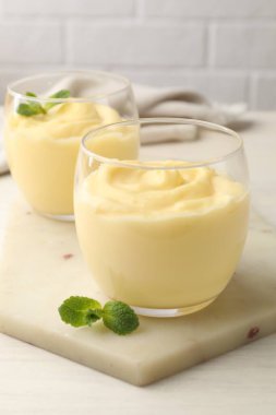 Beyaz ahşap masada naneli vanilyalı puding.