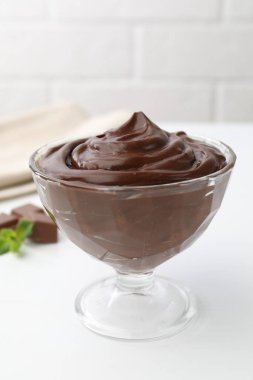 Tatlı kasesindeki çikolatalı puding beyaz masada, yakın plan.