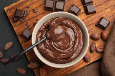 Kâsede lezzetli puding, çikolata ve kakao çekirdekleri siyah masada, düz yerde.