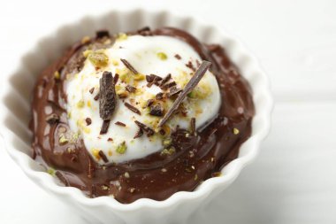 Lezzetli çikolatalı puding, beyaz ahşap masada krem şantili, yakın plan.