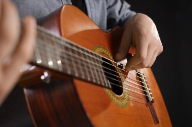 Siyah arkaplanda gitar çalan adam, yakın plan
