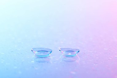 Kontakt lensler ve su damlaları mavi ayna yüzeyine, yakın plan.