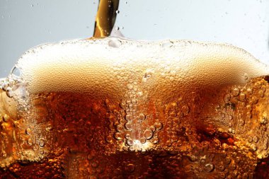 Açık gri arkaplan ve makro manzaraya buz küpleriyle ferahlatıcı kola dökülüyor