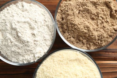 Tahta masadaki kaselerde farklı un türleri, üst görünüm.