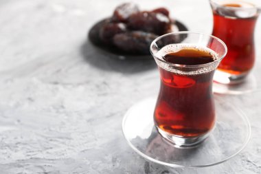 Geleneksel cam fincanlarda Türk çayı ve açık gri masada hurma, yakın plan. Metin için boşluk