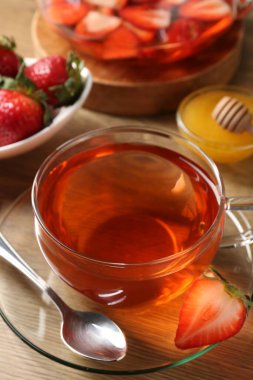 Çilekli Aromatik meyve çayı ve ahşap masada bal, yakın plan.