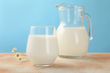 Taze süt ve çiçekler açık mavi arkaplanda, yakın plan