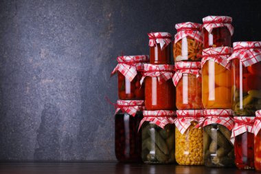 Ahşap masada farklı turşu ürünleri olan bir sürü kavanoz, metin için yer.