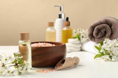 Beyaz masa üzerinde kozmetik ürünleri ve güzel çiçeklerle bej arka plan, seçici odak