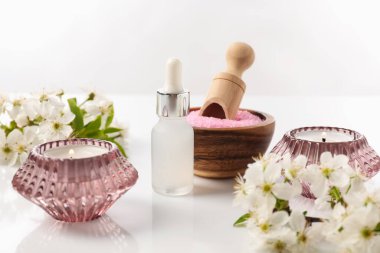 Kozmetik ürünleriyle spa kompozisyonu, yanan mumlar ve beyaz arka planda güzel çiçekler, yakın plan