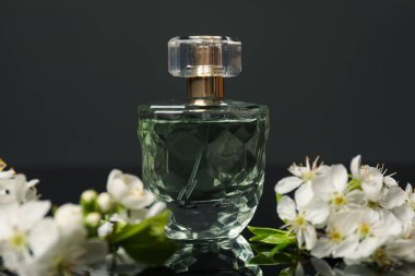 Aromatik parfüm ve siyah ayna yüzeyinde güzel çiçekler, yakın plan.