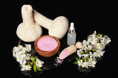 Siyah ayna yüzeyinde kozmetik ürünleri ve güzel çiçeklerle spa kompozisyonu