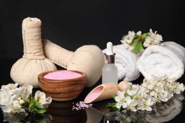 Siyah ayna yüzeyinde kozmetik ürünleri ve güzel çiçeklerle kaplıca kompozisyonu, yakın plan.