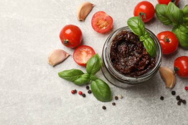 Lezzetli güneşte kurutulmuş domatesler, taze sebzeler, fesleğen ve sarımsak açık gri masada, düz yatıyordu.