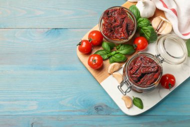 Lezzetli, kurutulmuş domatesler, taze sebzeler, fesleğen ve sarımsak mavi ahşap masa, üst manzara. Metin için boşluk