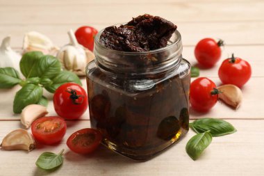 Lezzetli güneşte kurutulmuş domatesler, taze sebzeler, fesleğen ve sarımsak beyaz ahşap masada, yakın plan.