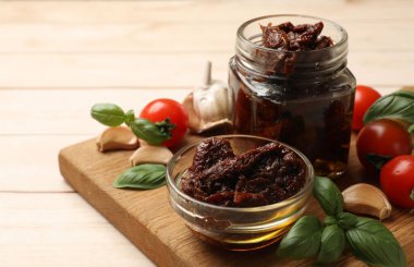 Lezzetli, kurutulmuş domatesler, taze sebzeler, fesleğen ve sarımsak beyaz ahşap masada, yakın plan. Metin için boşluk