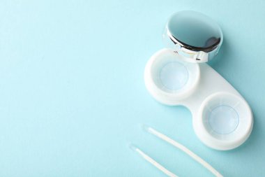 Açık turkuaz arka planda kontak lensler ve cımbızlar düz konumda. Metin için boşluk