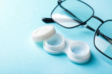 Açık mavi arkaplanda kontak lensler ve gözlükler, yakın plan