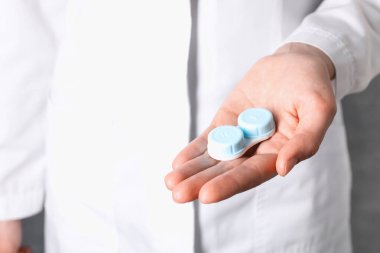 Gri arka planda kontak lensli doktor çantası, yakın plan.
