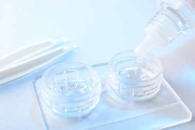 Işık arkaplanındaki kontakt lenslerle birlikte çözelti dosyaya damlıyor, yakın plan