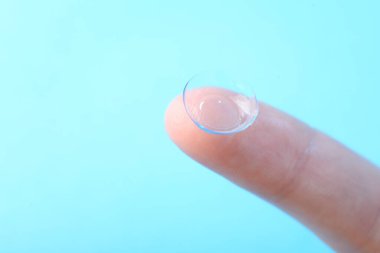 Açık mavi arka planda kontak lensli kadın, yakın plan. Metin için boşluk