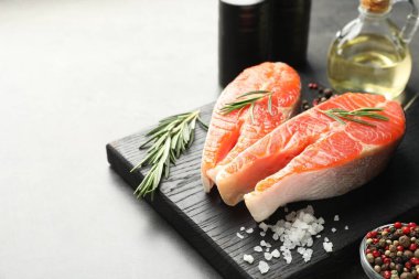 Deniz ürünleri. Çiğ somon bifteği, biberiye ve baharatlar gri masada, yakın plan. Metin için boşluk