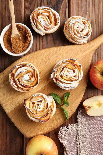 Ahşap masada servis edilen pudra şekerli lezzetli elma gülleri.