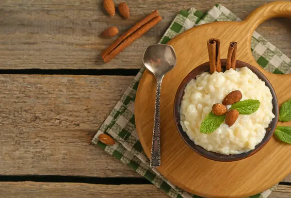 Bademli lezzetli sütlaç, nane ve tarçınlı çubuklar ahşap masa, düz yatak. Metin için boşluk