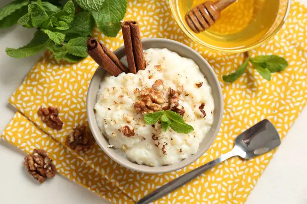Cevizli, tarçınlı, nane ve ballı leziz sütlaç beyaz masada, düz yerde.