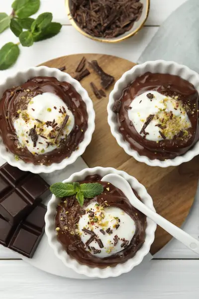 Krem şantili lezzetli puding, beyaz ahşap masa üzerinde çikolata ve kaşık parçaları, düz yatıyordu