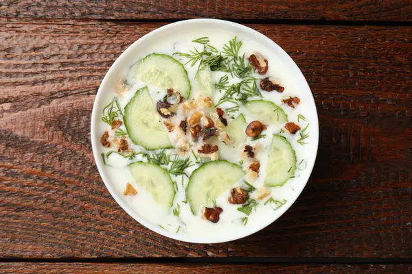 Ahşap masada dereotlu ve fındıklı lezzetli salatalık çorbası.